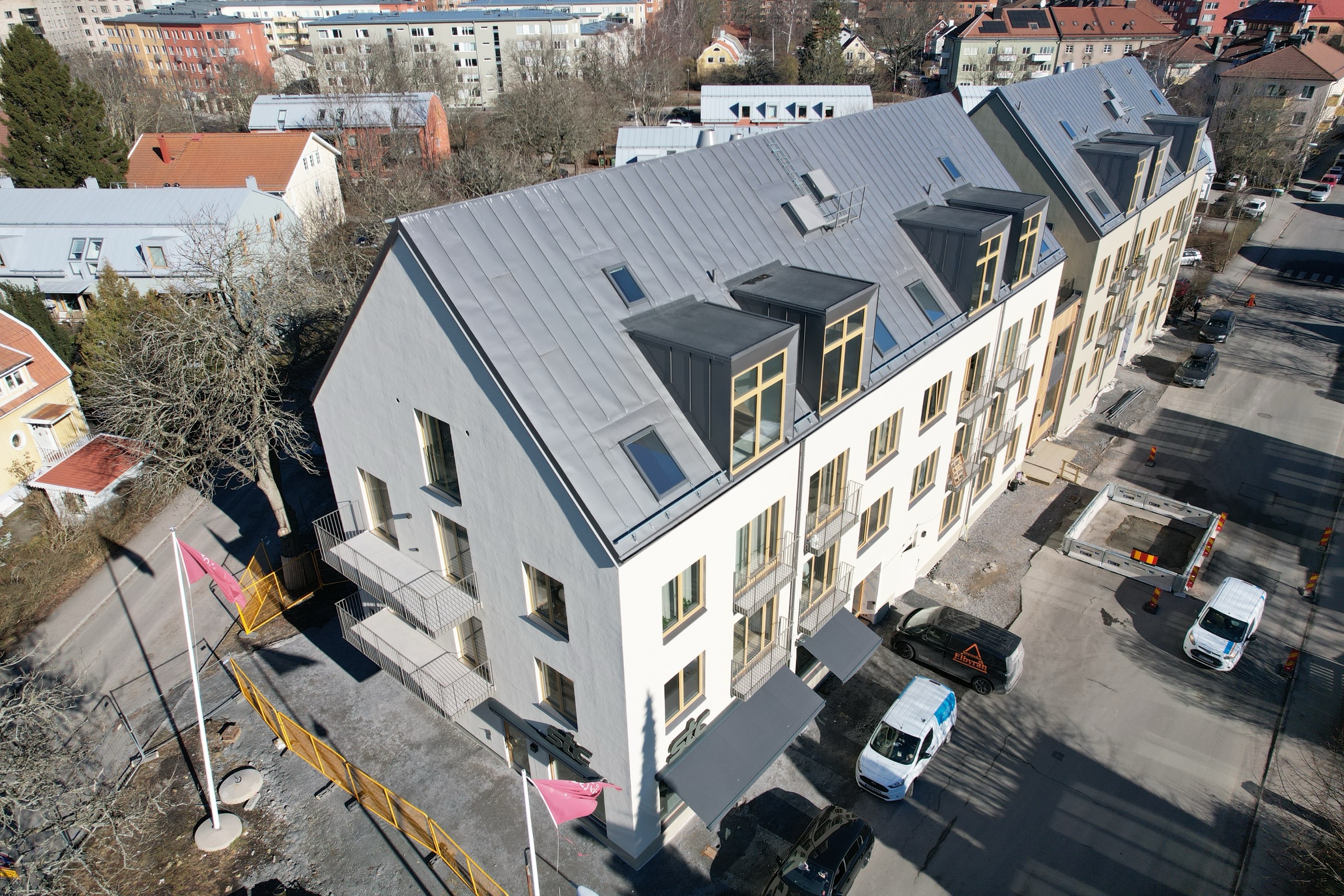Dubbelfalsat zink-plåttak — drönarvy över ny lägenhetsfastighet med fullständig fasligning, takkupor och takfönster utförd av Arbetslag Bygg